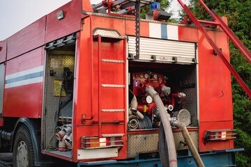Fire truck with hoses and equipment ready for emergency response in a lush green environment