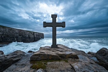 Large Christian Cross Carved Out of Stone Standing on Rocky Shore with Dramatic Sky and Waves Crashing Beneath, Perfect for Religious and Scenic Imagery