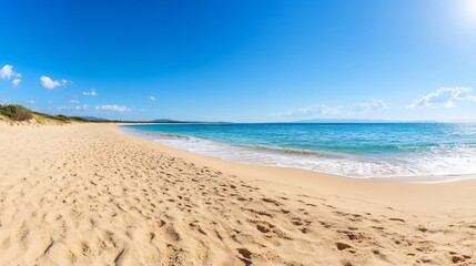 Footprints leading to the tranquil ocean under a bright sunny sky