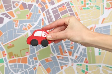 Woman with red toy car against city map, closeup. Road trip