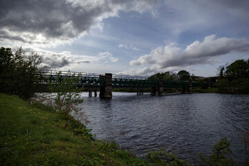Bridge spanning a serene river in the lush landscape of Scotland during a cloudy afternoon
