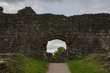 Exploring the ancient ruins of a Scottish castle on a cloudy day surrounded by lush greenery