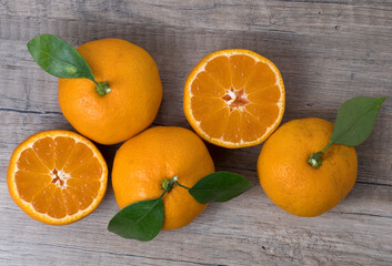 Fresh ripe tangerines with leaves on a wooden background.