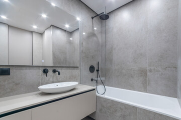 Modern bathroom design. A bathtub with a shower behind a glass partition. Stylish black .faucets.