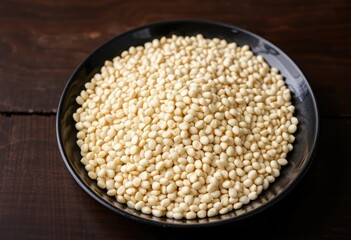 Raw buckwheat arranged neatly in a black plate, placed on a dark wooden table