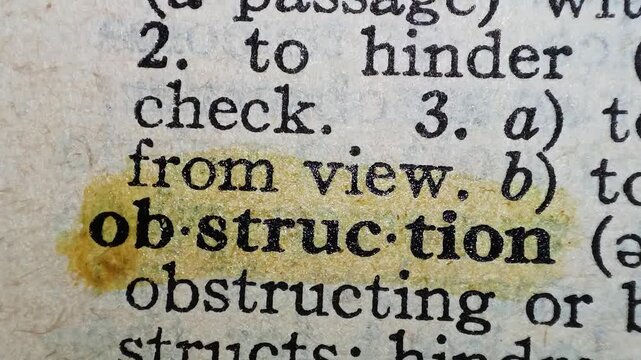 A man marks the definition from the word obstruction on a printed page with a marker tool