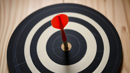 Red Dart Hitting Bullseye on Black and White Dartboard
