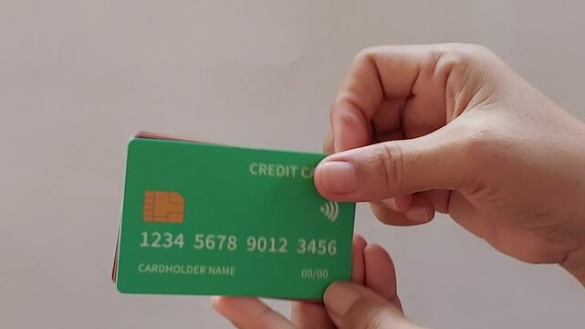 A man holds six colorful credit cards. The cards are maroon, orange, green, blue, white, and black.