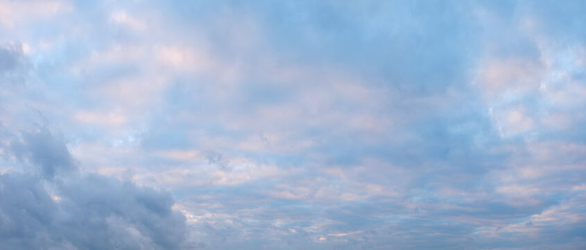 A blue sky with clouds and a pinkish hue. The sky is clear and the clouds are scattered throughout