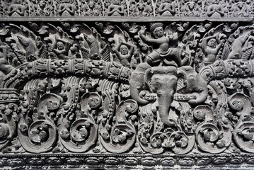 A wall with a lot of detail and a man riding an elephant