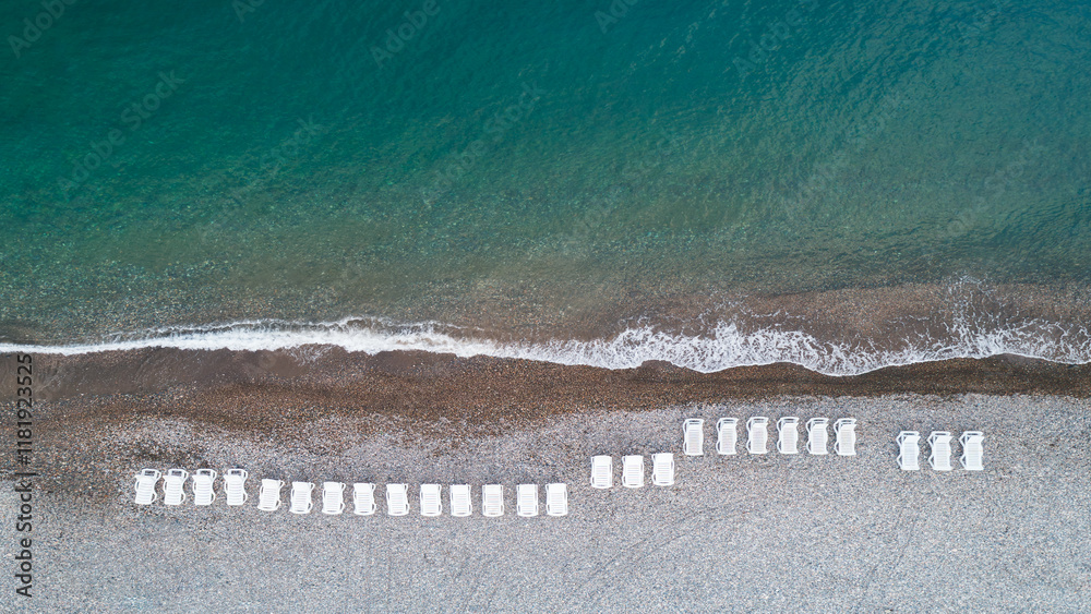 Aufkleber a beach with a row of white beach chairs. the chairs are lined up in a row, and the beach is calm an