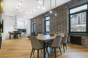 Stylish interior of a luxury studio apartment. Brick wall with a beautiful view from the .windows. Designer furniture.