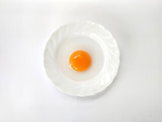 Duck egg yolk on a white plate on a white background.