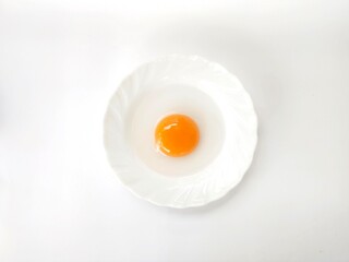 Duck egg yolk on a white plate on a white background.