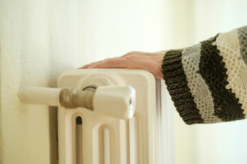 Senior woman checking temperature of home heating radiator