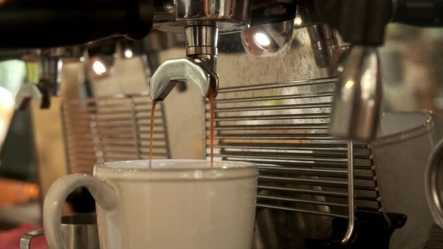 Close-up flowing fresh ground coffee. Pour coffee stream from the professional machine into the cup. Barista making double espresso with grinder oder filter holder. Drink a roasted black coffee