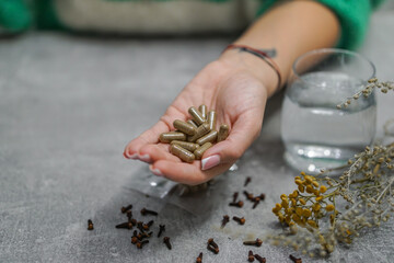 Woman hands holding handcrafted anti-parasitic detox capsules made with wormwood, clove, and a blend of natural herbs for holistic cleansing