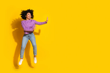 Full length photo of pretty young woman jump fight empty space isolated on yellow color background