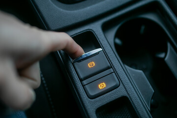 Car driver using fingers pushing electronic parking brake (EPB) in modern car for braking system