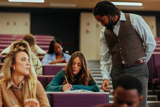 Professor assisting student during lecture in university classroom