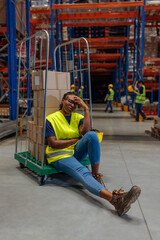 Exhausted warehouse worker resting on a metal cart
