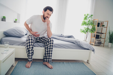 Photo of depressed sad mature guy dressed sleepwear sitting bed coughing indoors room home house