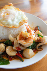 Stir fried mixed seafood with holy basil and fried egg on rice. Thai Food