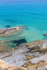Obraz premium Crystal Clear Turquoise Sea Waters Along the Rocky Coastline at Summer Day