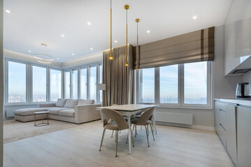 The interior of a modern studio with panoramic windows and a beautiful view of the city. Stylish furniture, beautiful decor.