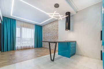 Modern design of the studio apartment. Stylish decor with blue curtains on the window and a blue kitchen set. Living area with parquet floor, unfurnished.