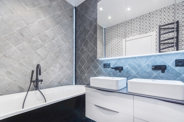 Exclusive interior design of the bathroom decorated with gray tiles. Stylish black faucets.