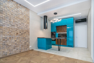 Luxury design of a modern studio apartment. Elegant kitchen set in blue with black accents. Living area with parquet floor and textured wooden wall.