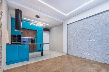 Stylish design of the studio apartment. Modern kitchen set in blue, black hood. Living area with parquet floors and original wall decoration.