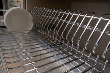 A clean and organized kitchen setup featuring a chrome dish rack with plates and cups.