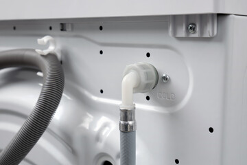 Close-up of a hose for connecting cold water to a washing machine in a house or apartment.