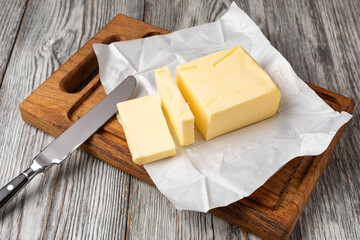 Butter slices with butter knife on wooden cutting board