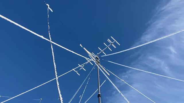 VHF radio antenna with stay ropes covered in snow against a blue sky.