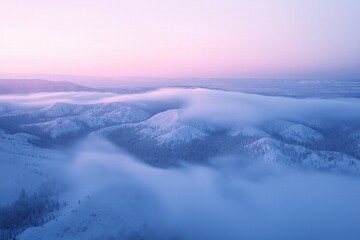 Obraz premium Majestic winter landscape with soft morning light over snow-covered hills and mist in the distance