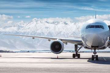 Front view of the white wide body passenger airplane at the airport on the background of high snow...