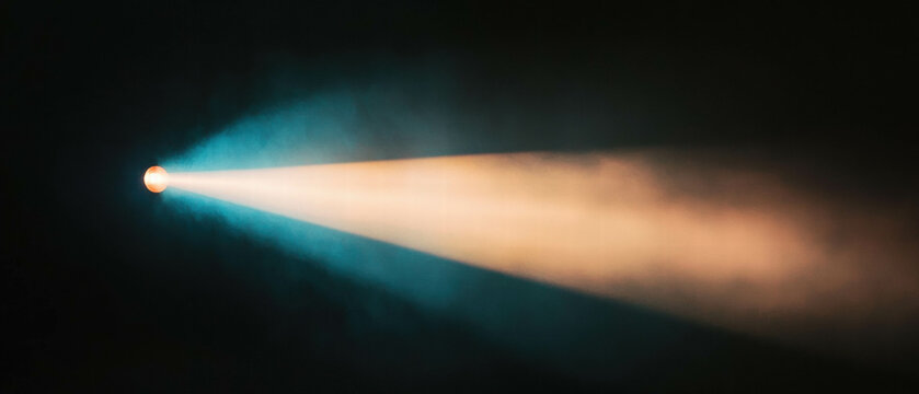 Spotlight creates dramatic light cone beams in a dark atmospheric setting