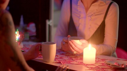 Two individuals are engaged in a tarot reading by candlelight, with tea cups on the table, creating an intimate atmosphere as they explore themes of divination and insights together