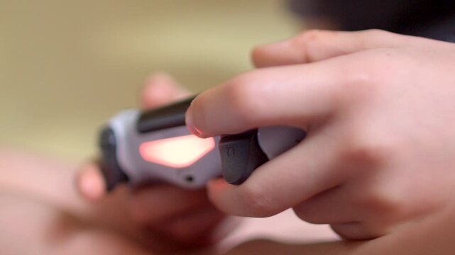 A closeup view of hands firmly gripping a PlayStation controller that features an illuminating LED light