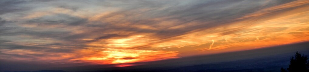 Colorful evening sky panorama during sunset over dark horizon of Silesian Beskids mountains with orange and red clouds. Topics: air space, weather, meteorology, sun energy, atmosphere, wallpaper