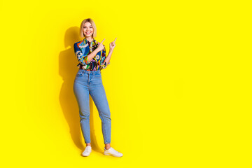 Full length photo of lovely young lady point empty space dressed stylish colorful garment isolated on yellow color background