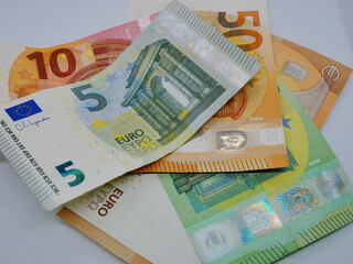 Pile of different euro bills paper banknotes, flat lay close up on a white background. The concept of saving, investment, finance, banking and economy