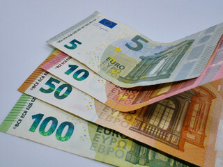 A stack of different euro bills paper banknotes, flat lay close up on a white background. The concept of saving, investment, finance, banking and economy