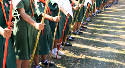A group of children wearing green uniforms holding flags