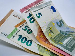 A stack of different euro bills paper banknotes, flat lay close up on a white background. The concept of saving, investment, finance, banking and economy