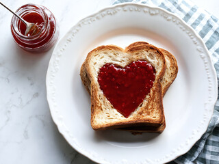 Toast shaped like a heart with jam served on a white plate for breakfast or snack time. Valentine’s Day idea, date, engagement party, love party, eat, food