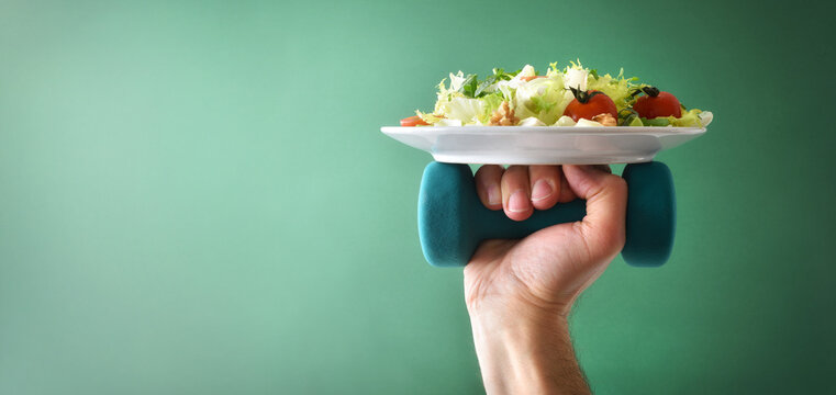 Healthy lifestyle background with hand holding dumbbell and salad